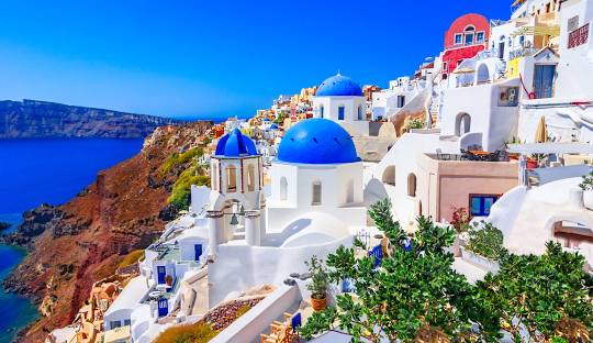 Beautiful coastal view of Santorini, Greece, featuring iconic white buildings, blue-domed churches, and the Aegean Sea.